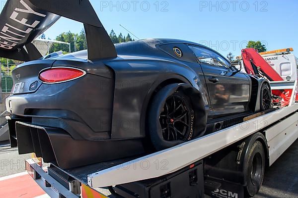 Bentley GT3 race car is taken back to Pit Lane of circuit by tow truck with punctured right rear tyre