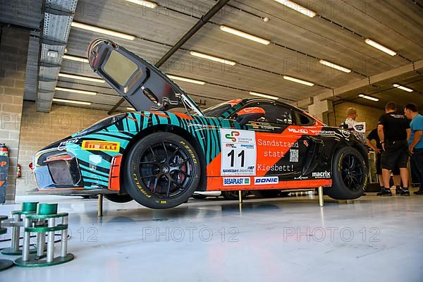 Racing car Porsche Cayman GT4 Clubsport MR stands on in car vehicle mounted stamp for lifting jacking up for tyre change in pit box of pit lane pit lane of race track