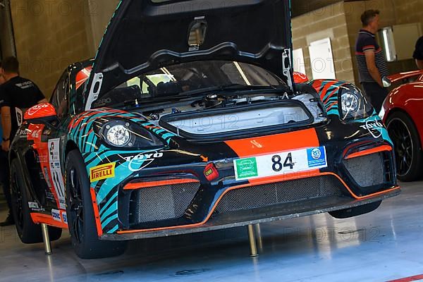 Racing car Porsche Cayman GT4 Clubsport MR stands on in car vehicle mounted stamp for lifting jacking up for tyre change in pit box of pit lane pit lane of race track