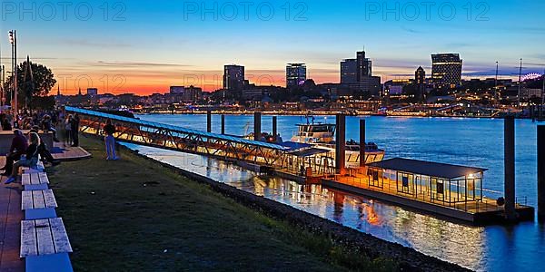 Pier for the harbour ferries at the Stage Theater on the Elbe in the evening in front of the city skyline