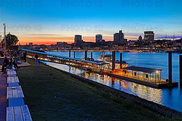 Pier for the harbour ferries at the Stage Theater on the Elbe in the evening in front of the city skyline