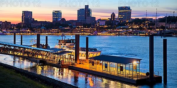 Pier for the harbour ferries at the Stage Theater on the Elbe in the evening in front of the city skyline