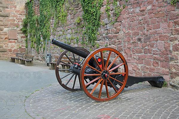 Historical cannon with wagon wheels in front of the town wall in Eberbach