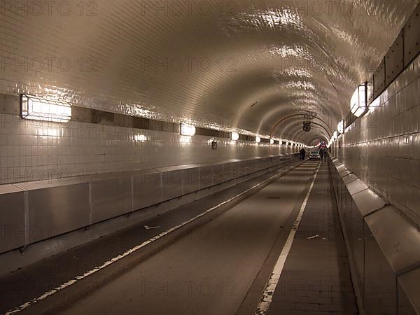 Pedestrians and a car cross the west tube of the old Elbe tunnel