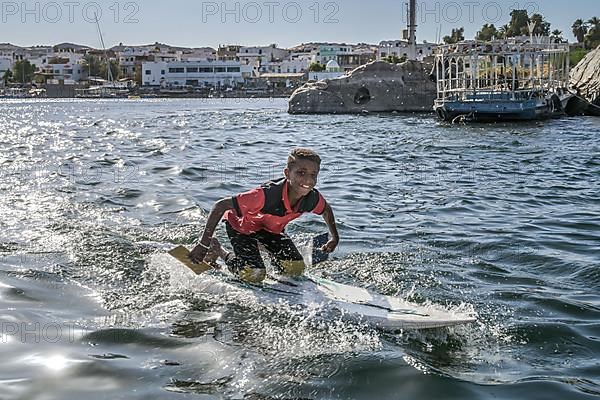 Boy on surfboard sings songs to tourists for money