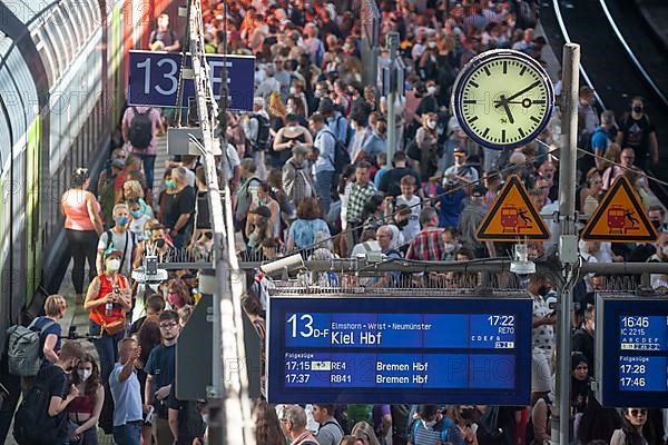 Many people standing crowded on a platform in front of a local train