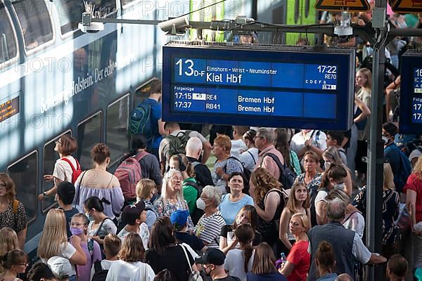 Many people standing crowded on a platform in front of a local train