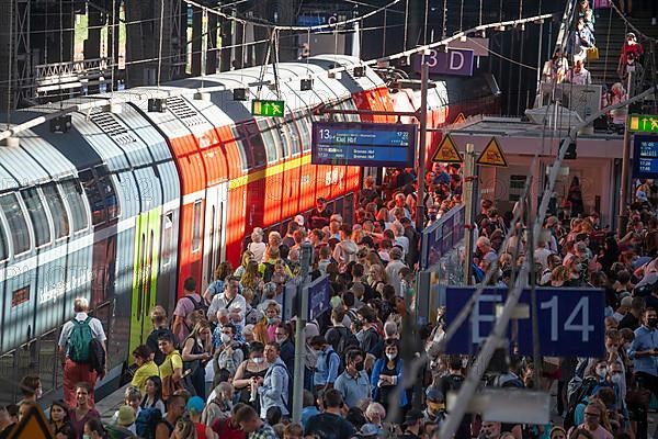 Many people standing crowded on a platform in front of a local train