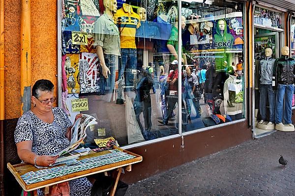 Lottery ticket seller in front of fashion shop