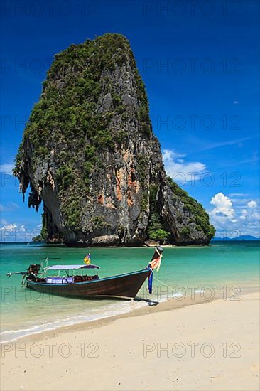 Long tail boat on tropical beach with limestone rock