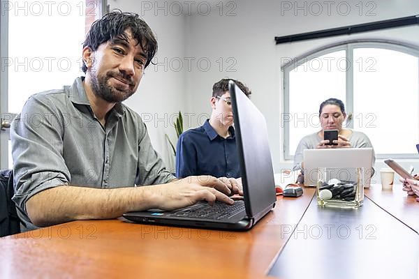 Group of employees sitting around the office meeting table working on their notebooks