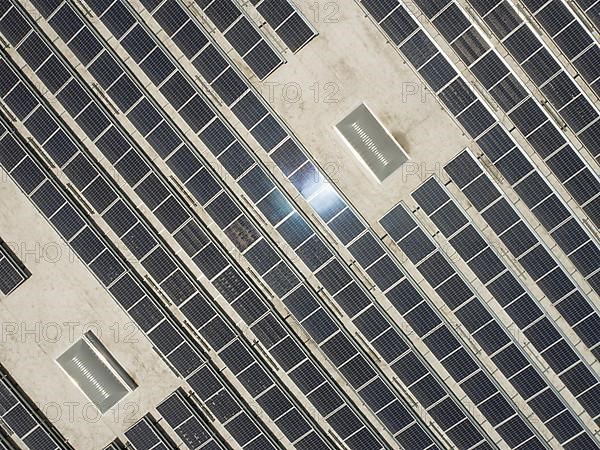 Aerial view of solar panels mounted on roof of large industrial building or warehouse