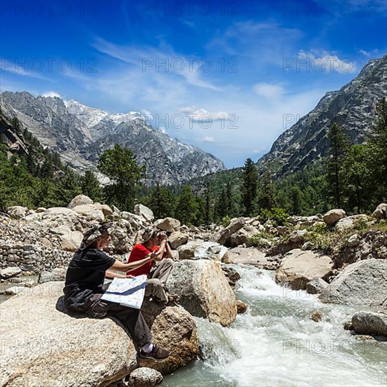 Hiker trekkers read a trekking map on trek in Himalayas mountains. Himachal Pradesh