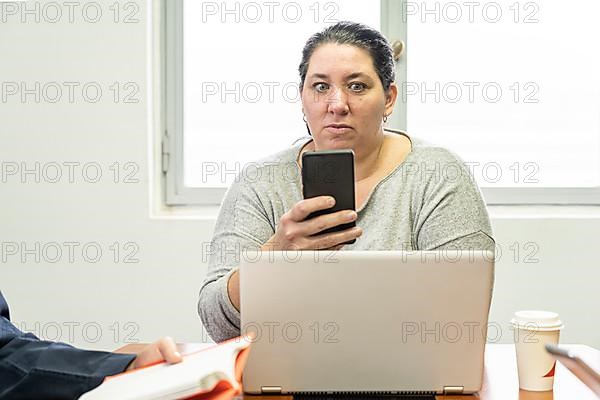 Mature business woman sitting at head of table in office meeting room