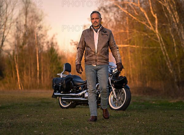 Middle-aged man in leather jacket heroically runs away from motorbike