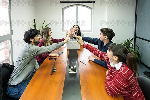 Cheerful office workers giving high five to colleagues