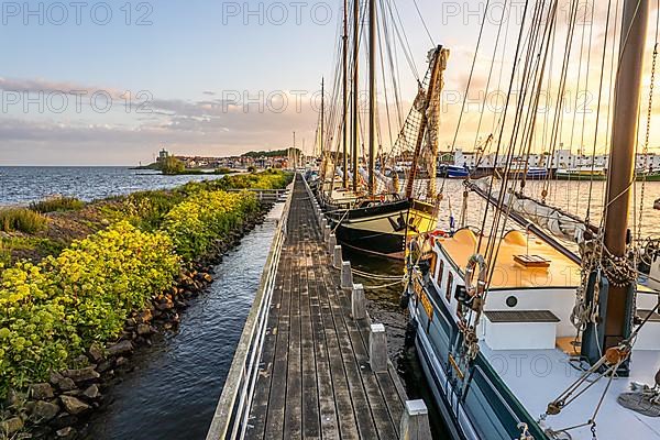 Wooden jetty with sailing ships in the sunset