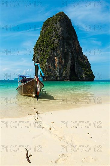 Long tail boat on tropical beach with limestone rock