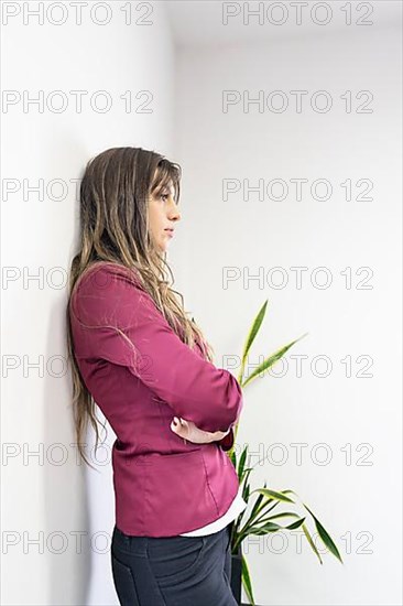 Young blonde businesswoman standing in meeting room with arms crossed