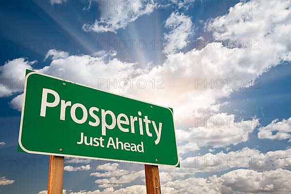 Prosperity green road sign over sunny dramatic clouds and sky