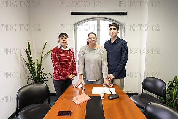 Group of employees standing at end of table in office meeting room