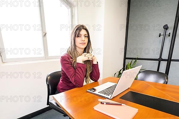 Young blonde business woman sitting at the head of the table in the office meeting room