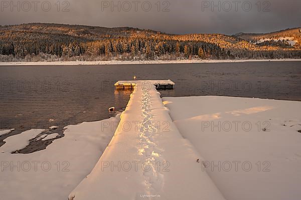 Snow-covered footbridge with footprints