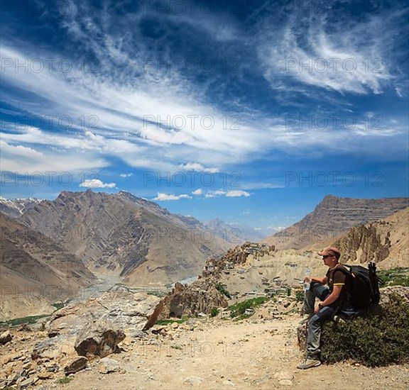 Mountaineer trekker tourist having rest and drinking water in Himalayas mountains