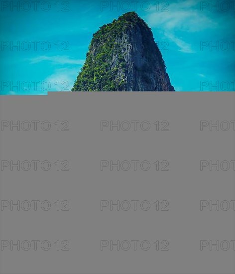 Long tail boat on tropical beach with limestone rock