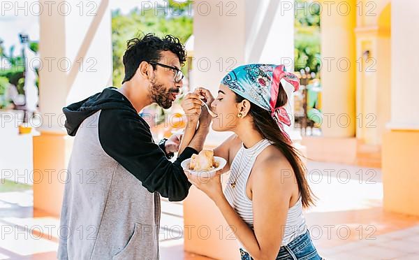 A couple eating shaved ice in a square