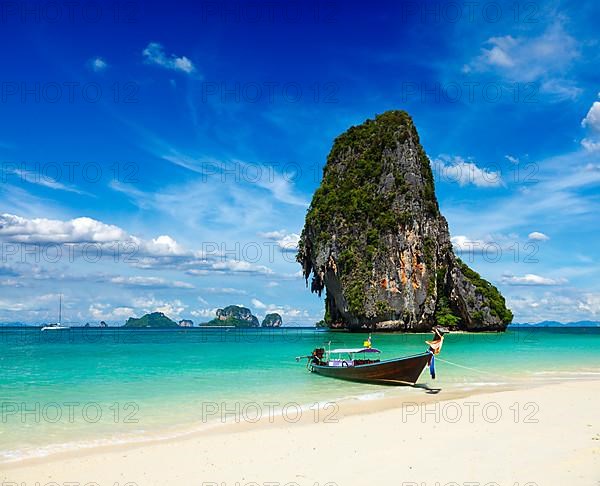 Long tail boat on tropical beach with limestone rock