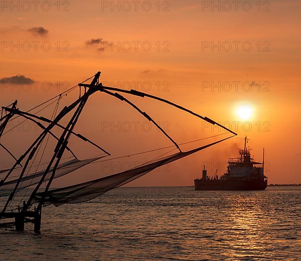 Kochi chinese fishnets on sunset and modern ship. Fort Kochin