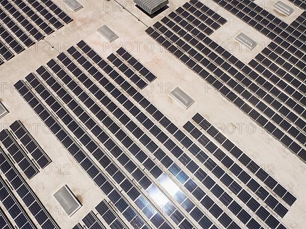 Aerial view of solar panels mounted on roof of large industrial building or warehouse