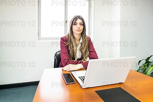 Young blonde business woman sitting at the head of the table in the office meeting room