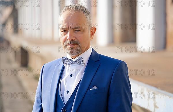 Man in blue suit and bow tie looks sceptical