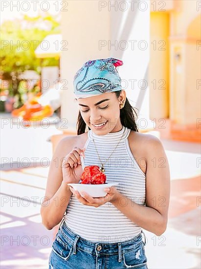 Young woman holding a cup of shaved ice on the street. Concept of a girl with a Nicaraguan raspado. Portrait of smiling girl holding shaved ice in the street. ICE SHAVING from Nagarote