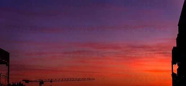 Construction crane in front of red-blue sky at sunset
