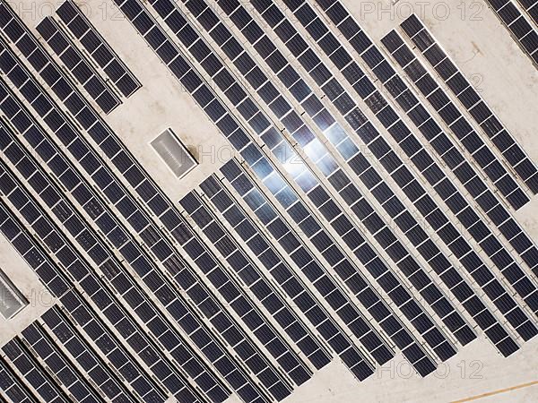 Aerial view of solar panels mounted on roof of large industrial building or warehouse