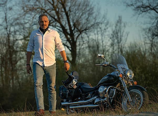 Man in white shirt and helmet in hand runs away from his motorbike