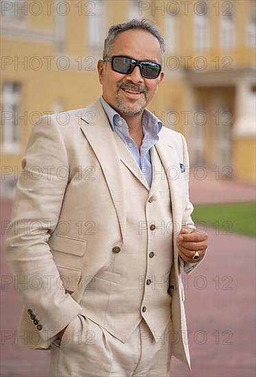 Man with sunglasses in suit standing in palace gardens