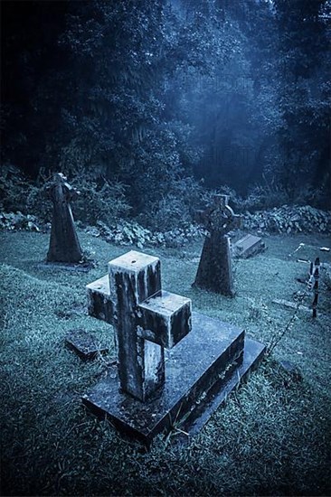 Spooky Halloween graveyard in fog in moonlight