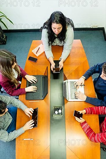 Top view of a group of employees sitting around office meeting table talking brainstorming