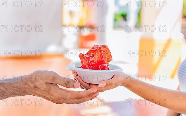 Two hands sharing a shaved ice in the street. Close up of two hands sharing a cup of shaved ice on the street. Concept of traditional Nicaraguan raspados. ICE SHAVING from Nagarote