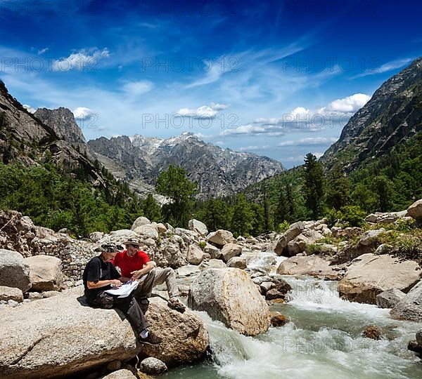 Hiker trekkers read a trekking map on trek in Himalayas mountains. Himachal Pradesh