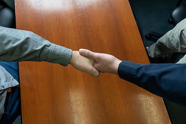 Close-up overhead shot of two men shaking hands. Concept of deal