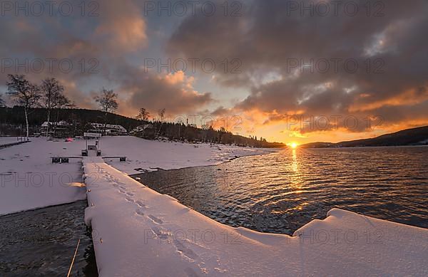 Snowy footbridge at the lake at sunrise