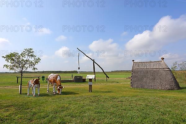 Drawing well and reed hut with cows sculpture