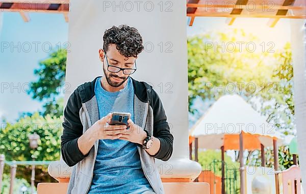 Handsome guy in glasses leaning on a wall chatting on his cell phone