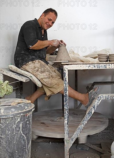 Moroccan potter at work: turning at the potter's pane and shaping ceramic vessels and pottery: Jugs