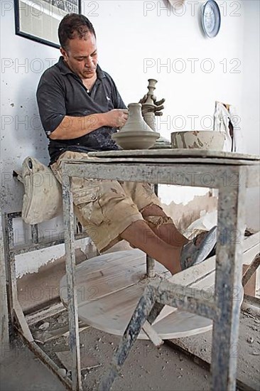 Moroccan potter at work: turning at the potter's pane and shaping ceramic vessels and pottery: Jugs